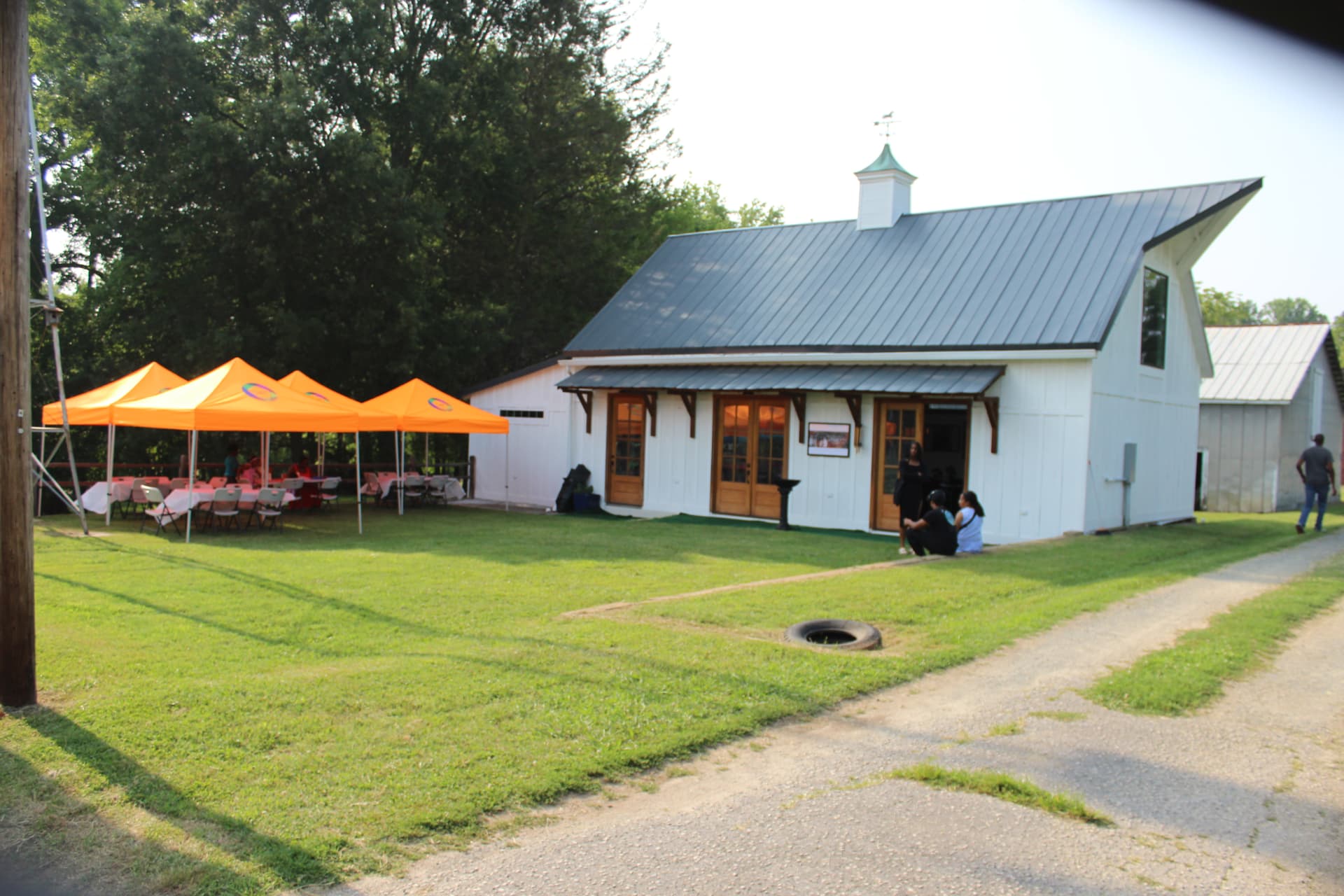 Neighbors gathered outdoors under orange tents beside a community building